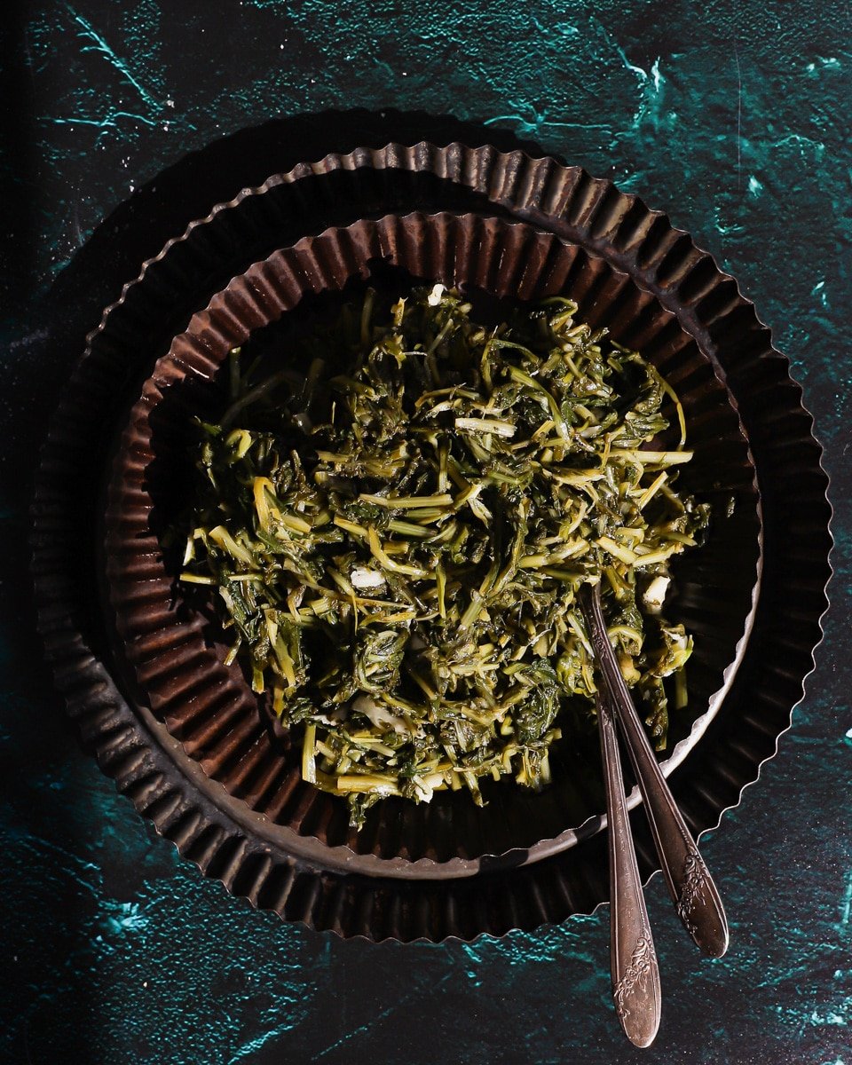 dandelion salad on a plate with 2 forks