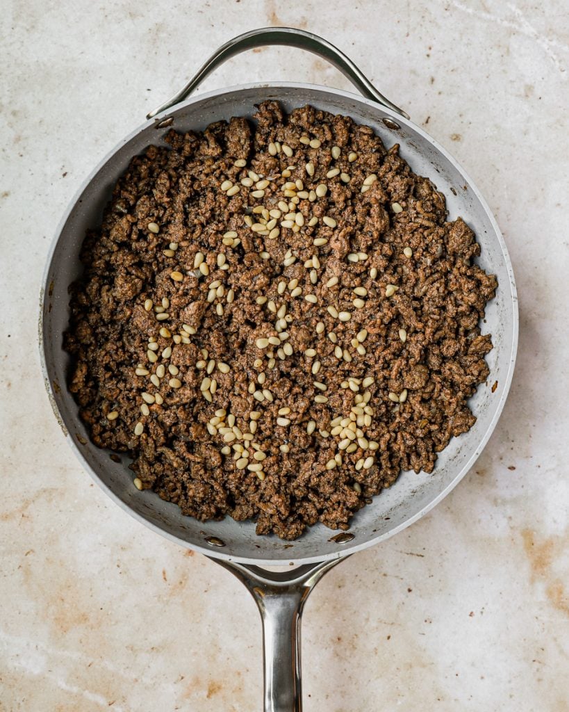 Ground beef and pine nuts in skillet