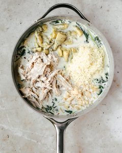 pan with sauce, chicken, artichokes, cheese