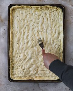Fork piercing dough in sheet pan