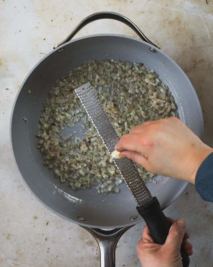 grating garlic with microplane over pan