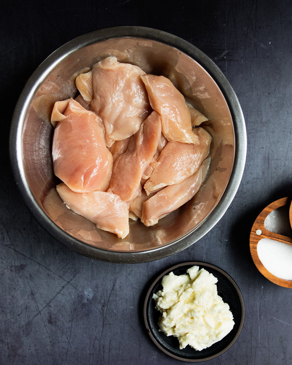 chicken breast, toum and salt in bowls - ingredients for grilled chicken