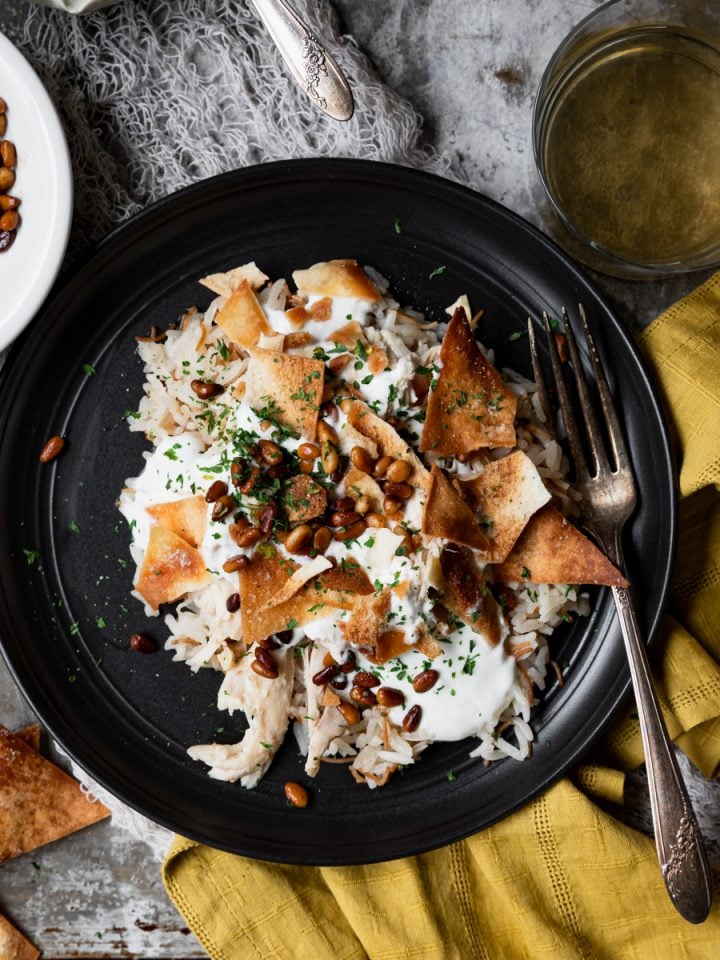 Plate of fattah - rice, chicken, toasted pita and pine nuts with yogurt sauce