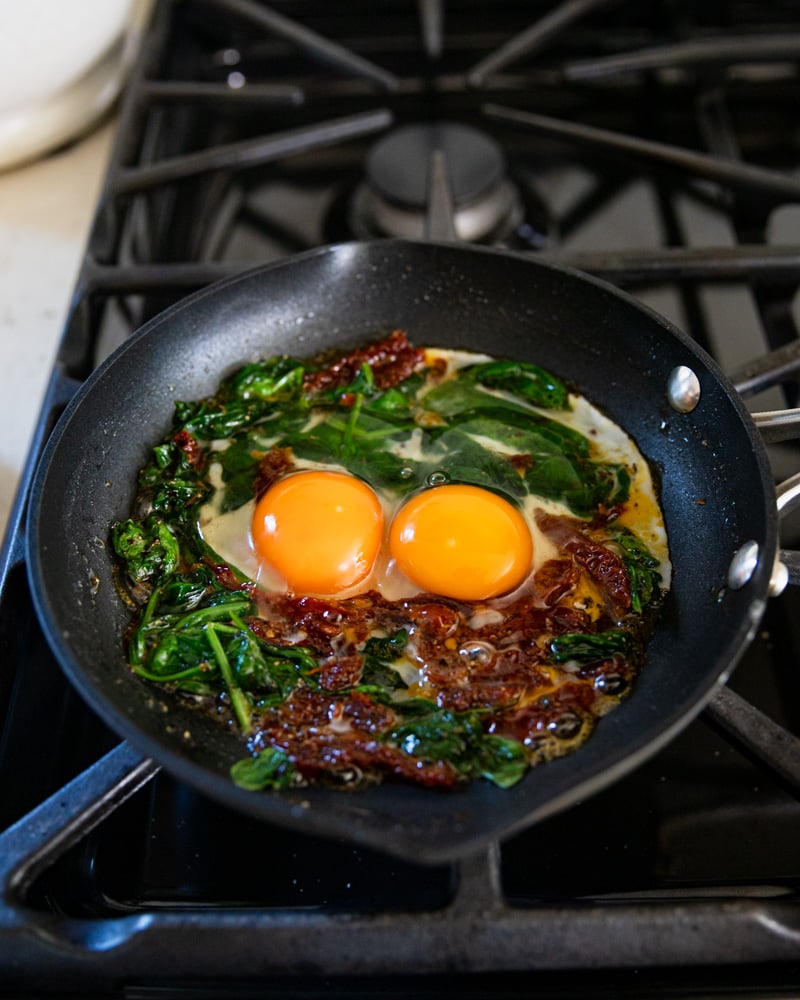 eggs in skillet on spinach mixture